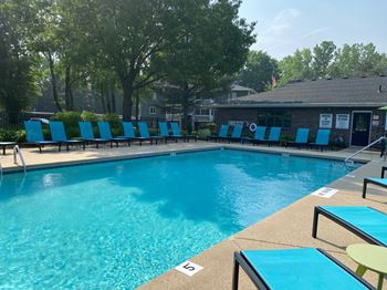 A pool with blue chairs and a building in the background.